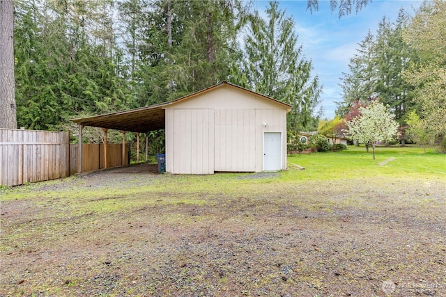 view of outdoor structure featuring an outbuilding, a carport, and fence