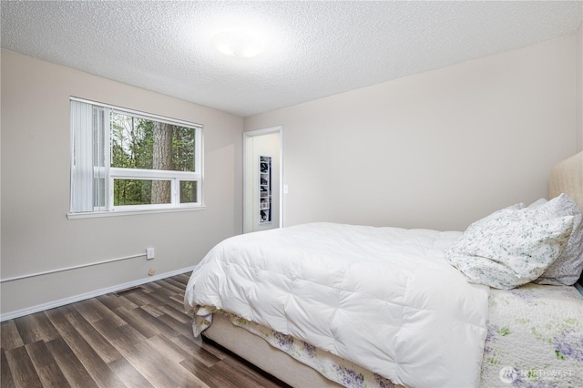 bedroom featuring a textured ceiling, visible vents, wood finished floors, and baseboards