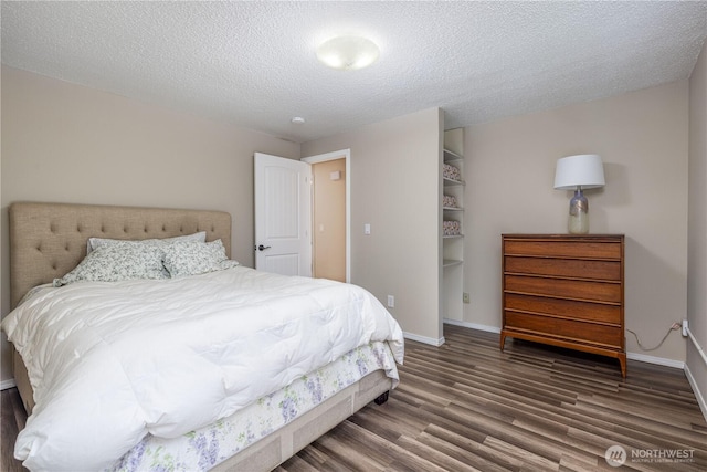 bedroom with a textured ceiling, wood finished floors, and baseboards