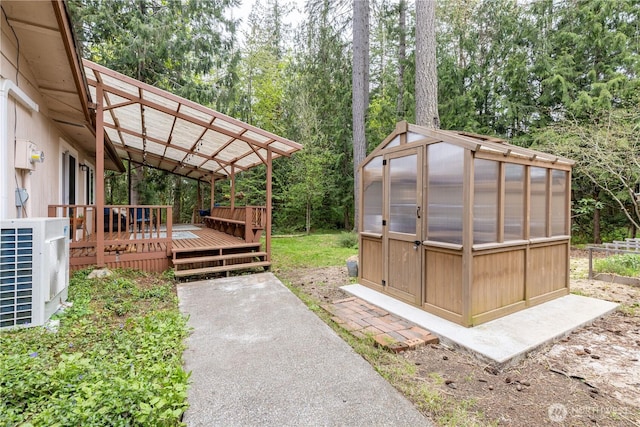 view of yard with a deck, central air condition unit, an outbuilding, and a greenhouse