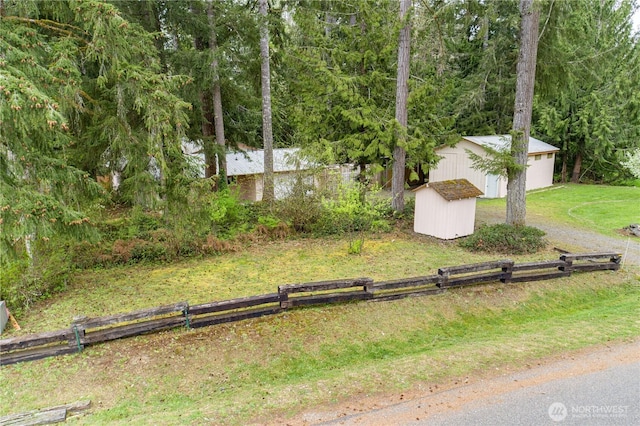 view of yard with an outbuilding, a shed, a forest view, and fence