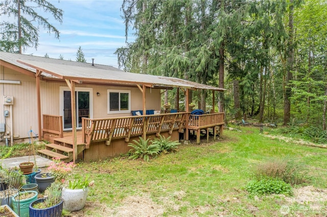 rear view of property with a deck, a yard, and metal roof