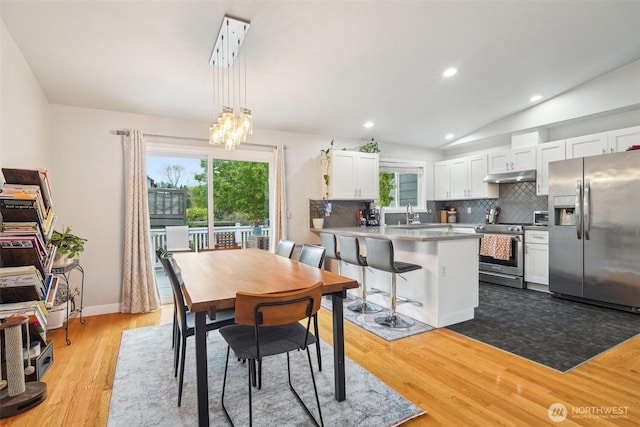 dining space featuring recessed lighting, lofted ceiling, wood finished floors, and a notable chandelier