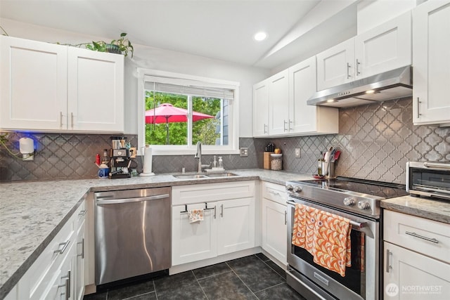 kitchen with under cabinet range hood, white cabinets, dark tile patterned flooring, a sink, and stainless steel appliances