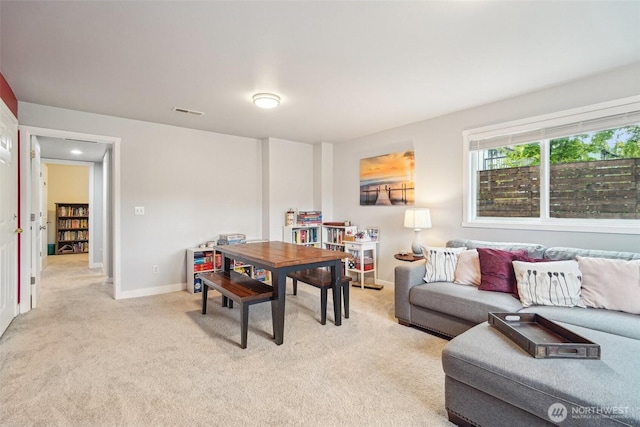living area with baseboards, light colored carpet, and visible vents