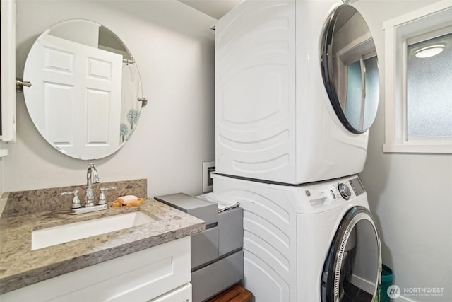 washroom featuring stacked washing maching and dryer and a sink