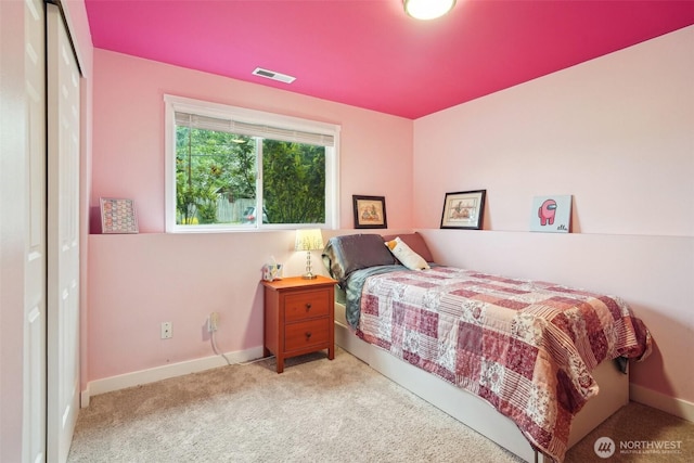 carpeted bedroom featuring baseboards, a closet, and visible vents