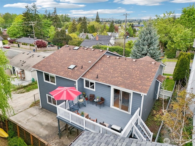 rear view of property featuring roof with shingles, fence, and a deck