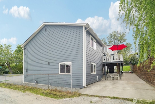 view of side of property with a patio, a wooden deck, and fence