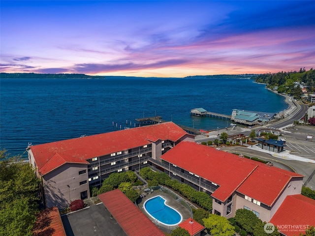 aerial view at dusk featuring a water view