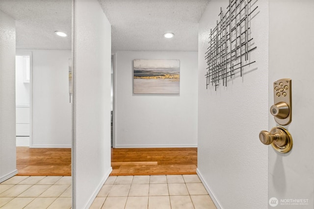 hallway featuring tile patterned flooring, a textured ceiling, and baseboards