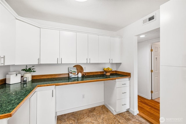 kitchen with visible vents, baseboards, white cabinets, and dark countertops