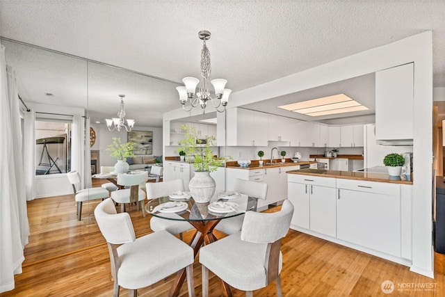 dining area featuring an inviting chandelier, a textured ceiling, and light wood finished floors