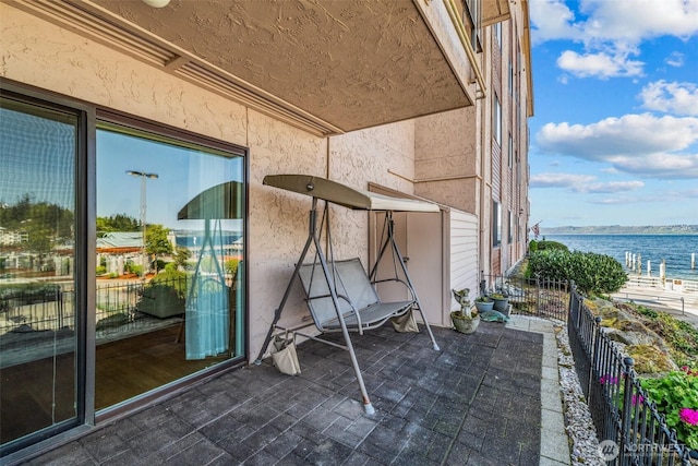 view of patio featuring a water view and fence