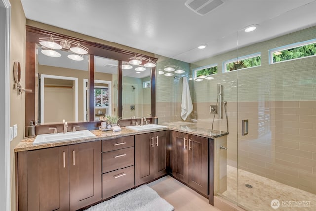 full bathroom featuring a sink, a shower stall, double vanity, and visible vents