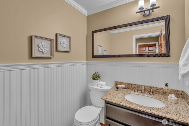 bathroom with crown molding, vanity, wainscoting, and toilet