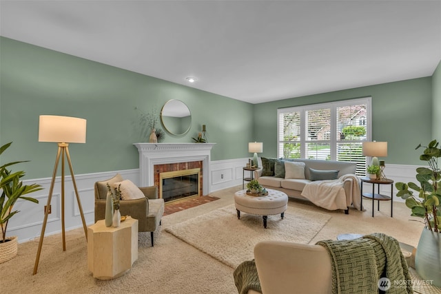 living area featuring a fireplace with flush hearth, carpet floors, wainscoting, and a decorative wall