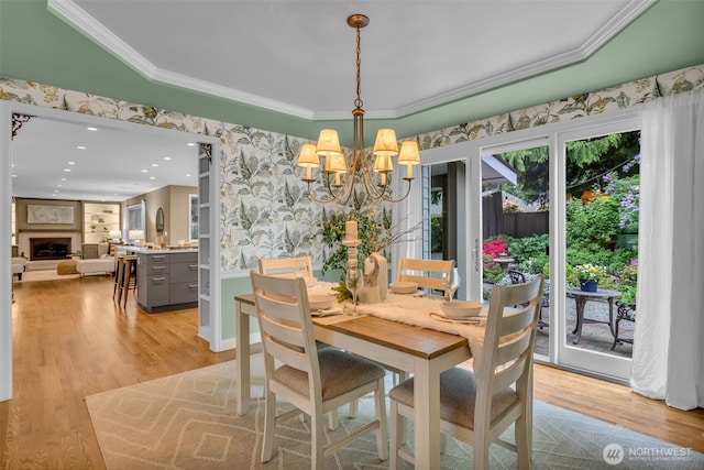 dining room featuring crown molding, wallpapered walls, an inviting chandelier, and light wood-type flooring