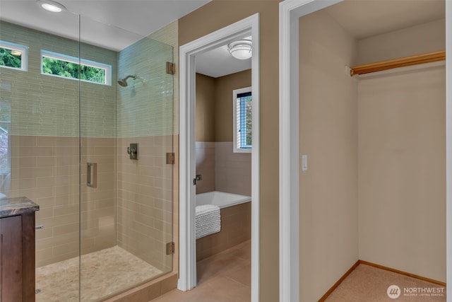 bathroom featuring baseboards, a garden tub, and a stall shower