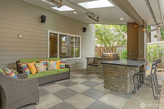 view of patio featuring fence, outdoor wet bar, area for grilling, an outdoor living space, and a grill