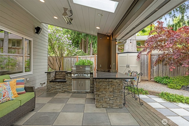 view of patio / terrace featuring a storage unit, outdoor wet bar, exterior kitchen, a fenced backyard, and a grill