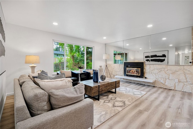 living room with a glass covered fireplace, recessed lighting, and wood finished floors