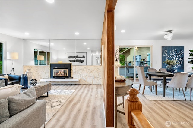 living room featuring a glass covered fireplace, recessed lighting, and wood finished floors