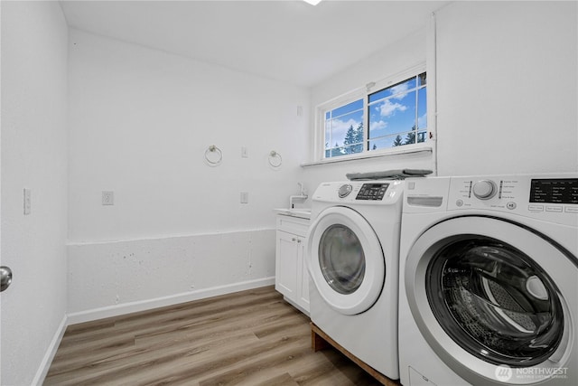 clothes washing area with baseboards, light wood finished floors, washer and dryer, and cabinet space