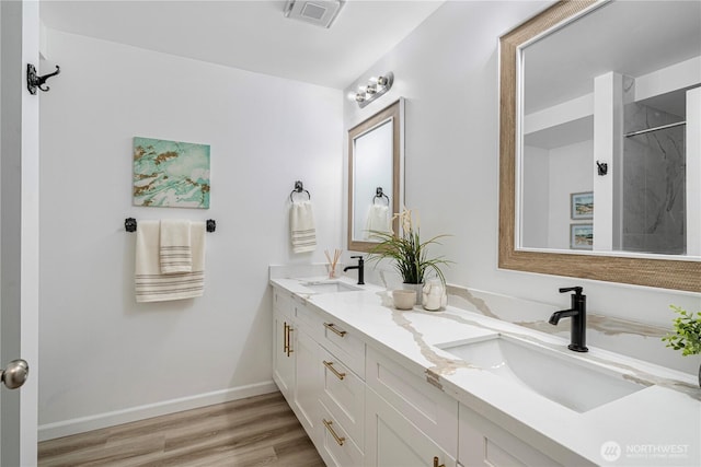 full bathroom featuring a sink, double vanity, visible vents, and wood finished floors