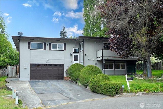 bi-level home with driveway, an attached garage, and fence