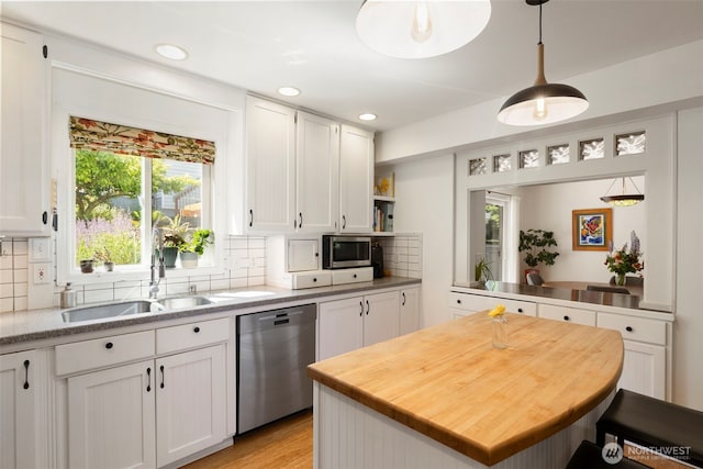 4375 Erin St, Port Townsend, WA 98368 - kitchen featuring appliances with stainless steel finishes, a sink, white cabinetry, decorative backsplash, and decorative light fixtures