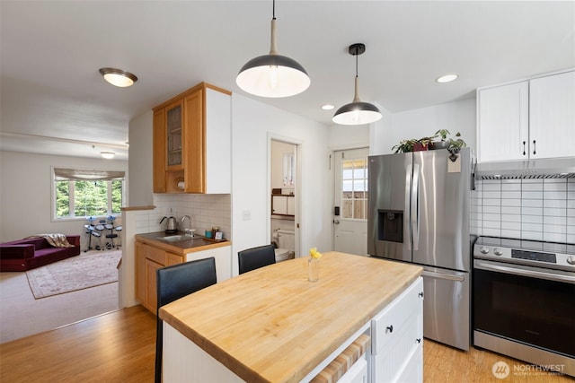 4375 Erin St, Port Townsend, WA 98368 - kitchen featuring stainless steel appliances, under cabinet range hood, a sink, backsplash, and light wood-type flooring