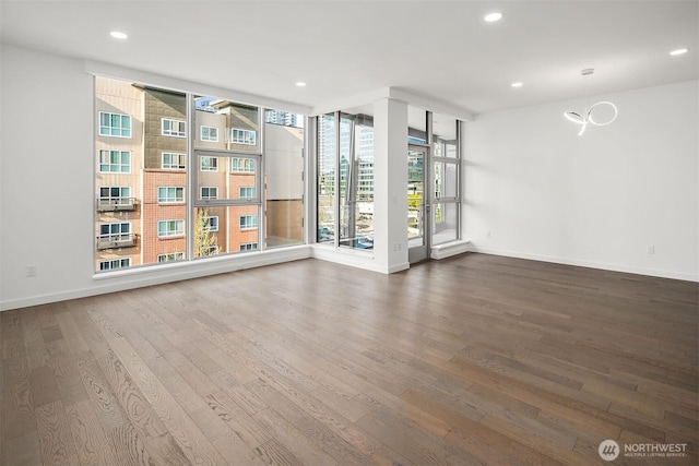 spare room with baseboards, recessed lighting, and wood finished floors