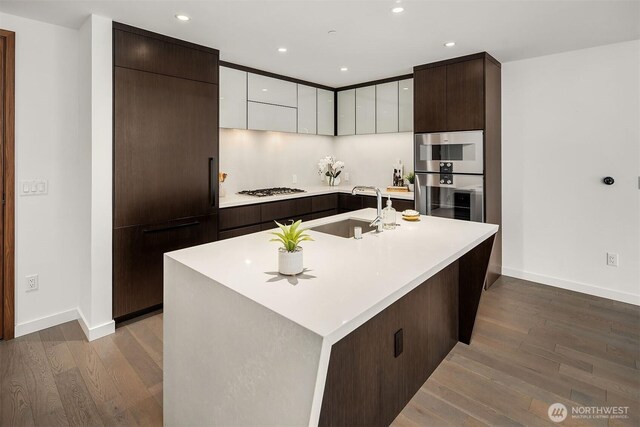 kitchen with light countertops, stainless steel appliances, baseboards, and a sink