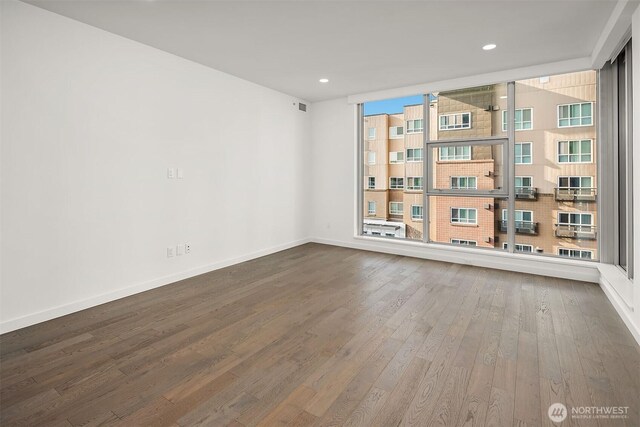 spare room with baseboards, recessed lighting, wood finished floors, and visible vents