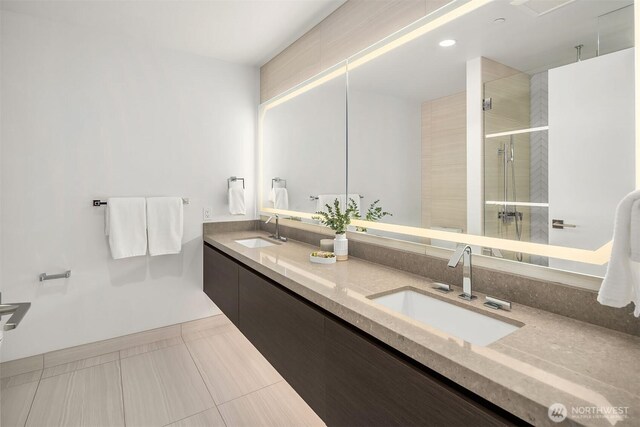 full bath with a sink, tile patterned floors, a stall shower, and double vanity