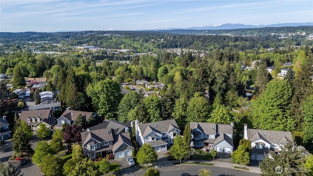 aerial view of property's location with a forest, nearby suburban area, and mountains