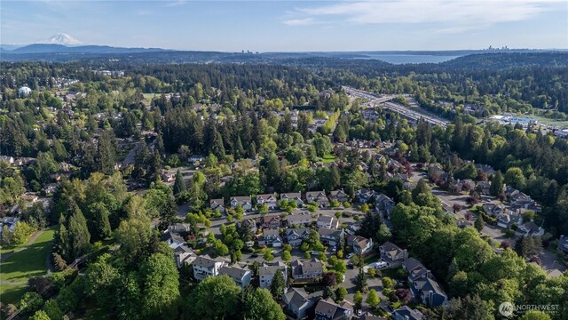 view of property location featuring a forest, mountains, and nearby suburban area