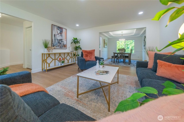 living area with wood finished floors, a raised ceiling, recessed lighting, and baseboards