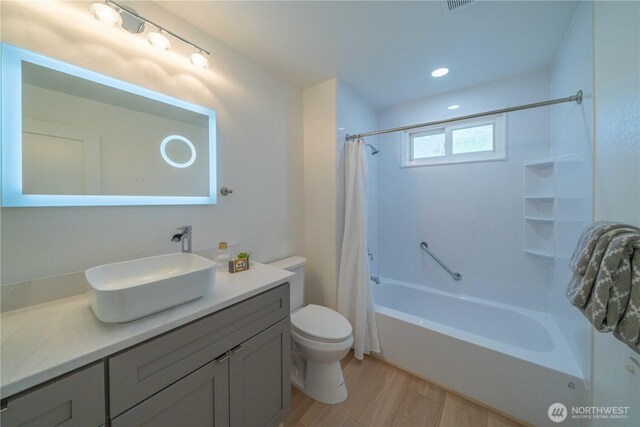 full bathroom featuring wood finished floors, toilet, shower / bath combo with shower curtain, vanity, and recessed lighting