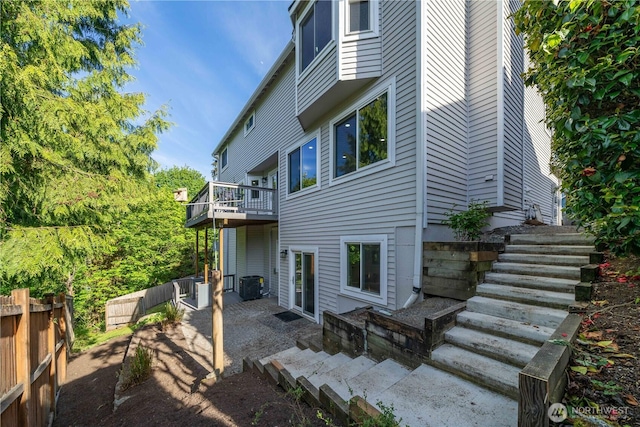 back of property with fence, central air condition unit, and stairs
