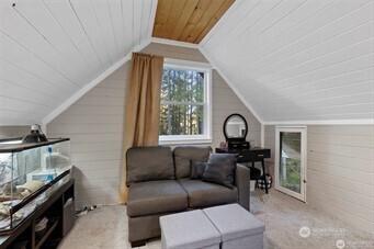 bonus room with wooden walls, light carpet, wood ceiling, and lofted ceiling