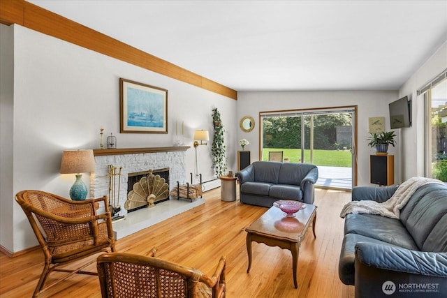 living room featuring a baseboard radiator, a fireplace with raised hearth, and wood finished floors
