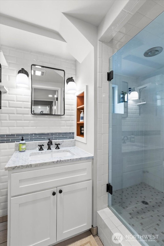 bathroom with vanity, decorative backsplash, and a stall shower