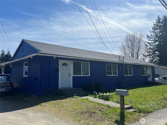ranch-style house featuring a front lawn and roof with shingles