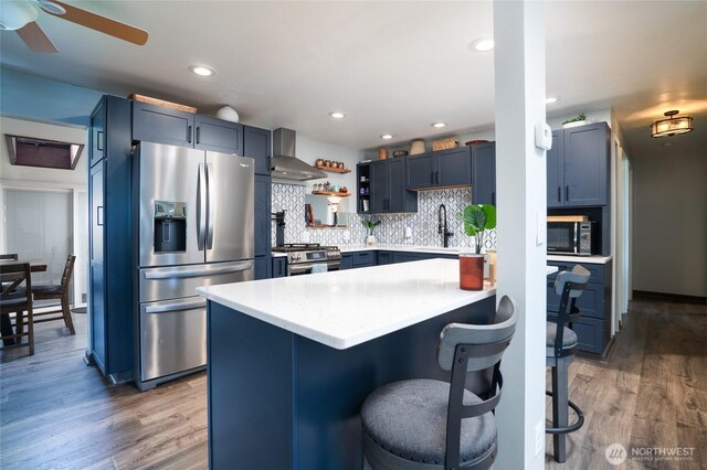 1705 36th St, Anacortes, WA 98221 - kitchen featuring stainless steel appliances, wall chimney range hood, a breakfast bar area, light wood finished floors, and recessed lighting