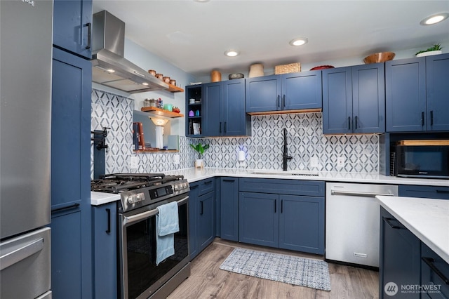 1705 36th St, Anacortes, WA 98221 - kitchen featuring appliances with stainless steel finishes, island exhaust hood, a sink, blue cabinets, and recessed lighting