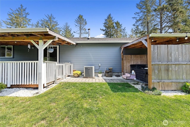 rear view of house with a yard, cooling unit, and roof with shingles
