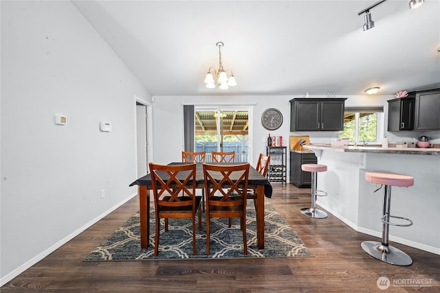 dining space with baseboards, lofted ceiling, dark wood finished floors, and a chandelier