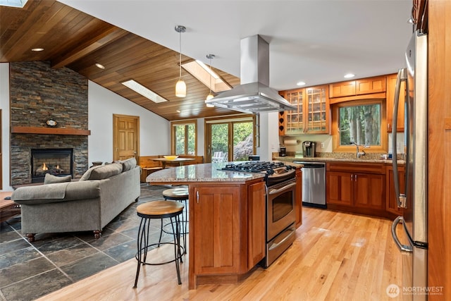12105 SE 23rd St, Bellevue, WA 98005 - kitchen with brown cabinetry, light stone counters, a kitchen breakfast bar, island exhaust hood, and stainless steel appliances